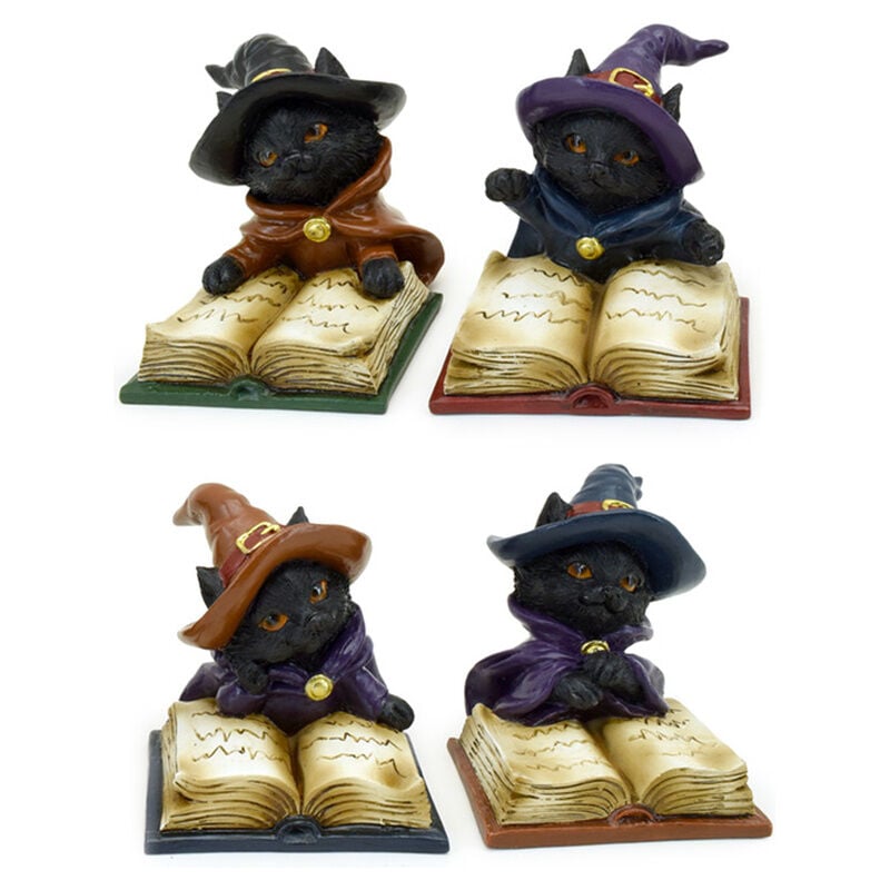 Figura de gato negro brujo sobre un libro de hechizos