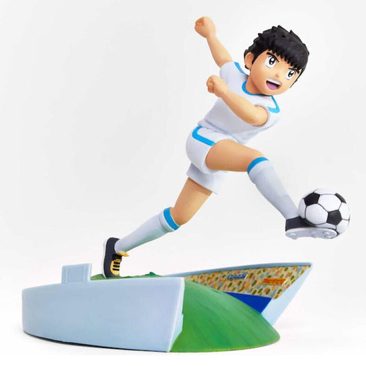 Figura de Oliver Atom chutando un balón sobre una base futbolística