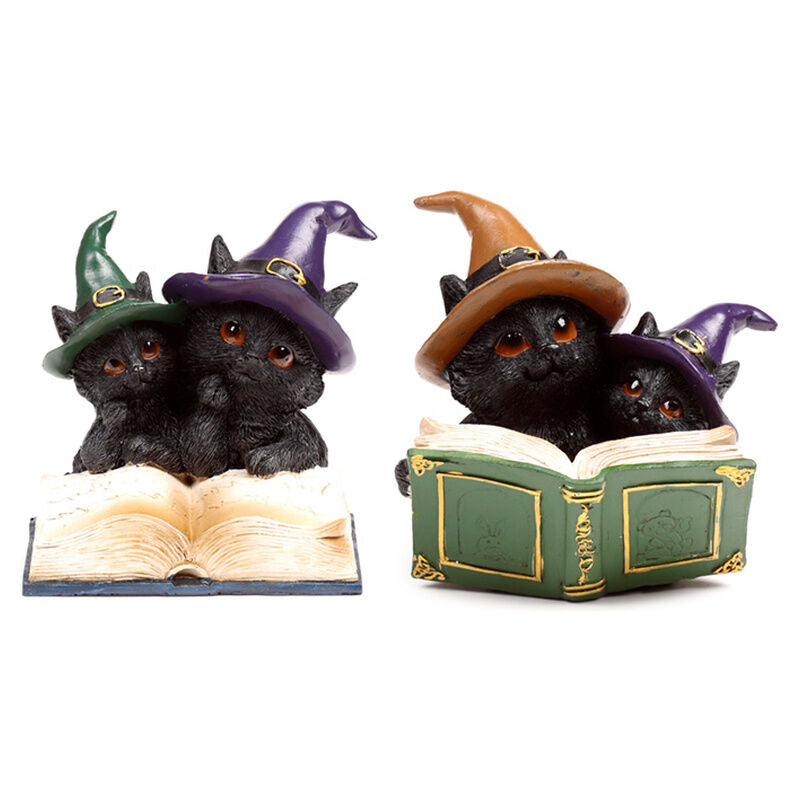 Figuras de gatos negros con sombreros de bruja sobre libros