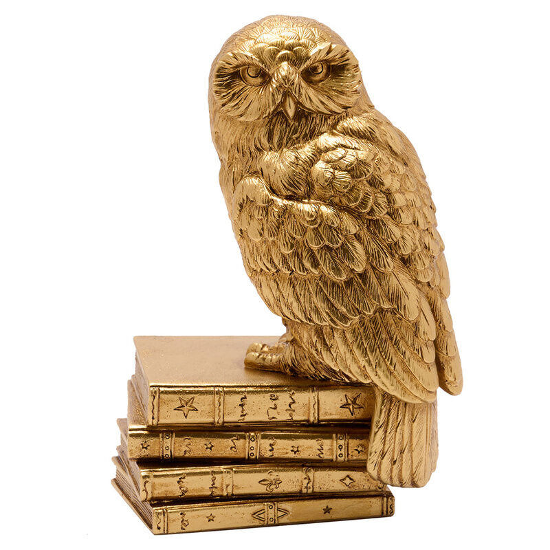 Figura dorada de Hedwig de Harry Potter sobre una pila de libros